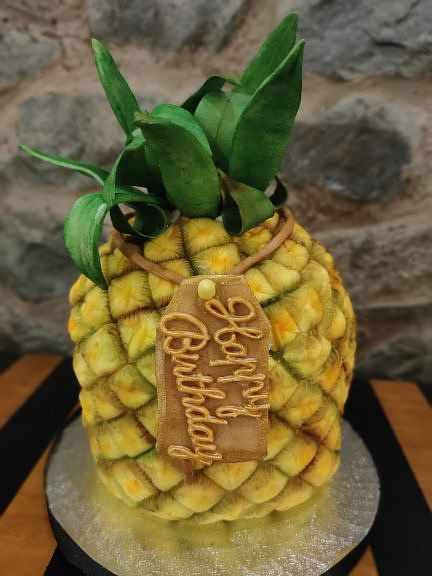 A sponge cake with icing, sculpted into a pineapple.